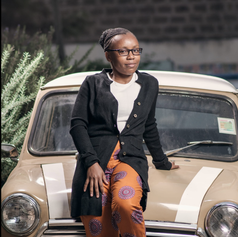 Emma Karuri, founder of CalmFriction, sitting on a vintage car